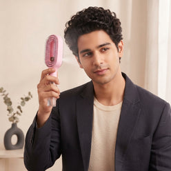 Portrait of Indian influencer Ishaan Malhotra holding a 2-in-1 spray comb for hair against a clean studio background.