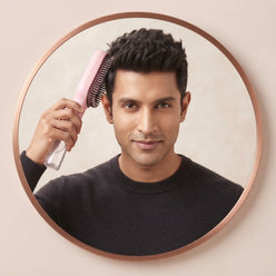A circular portrait of a South Asian man holding a 2-in-1 spray comb against a minimalist cream background.